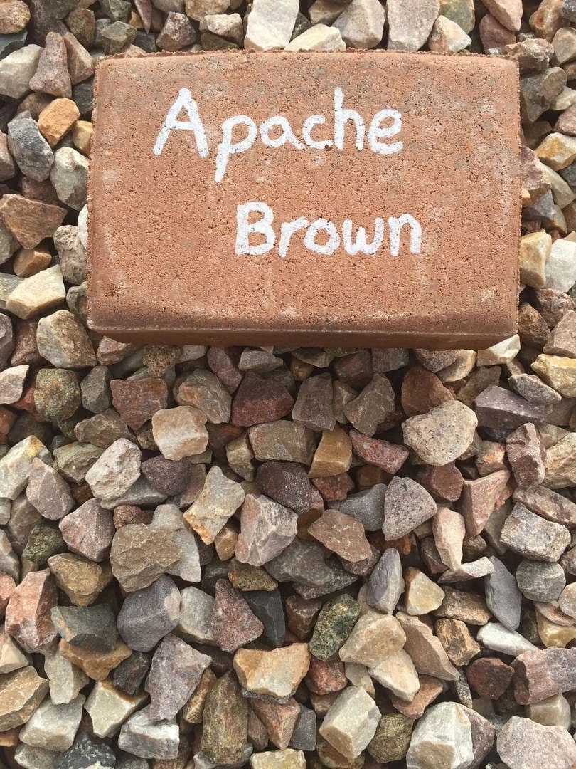 Apache Brown rock sample on a bed of small colorful stones, ideal for landscaping projects.